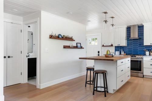 a kitchen with white cabinets and a counter and stools at Perch - Greenbank Cottage in Greenbank