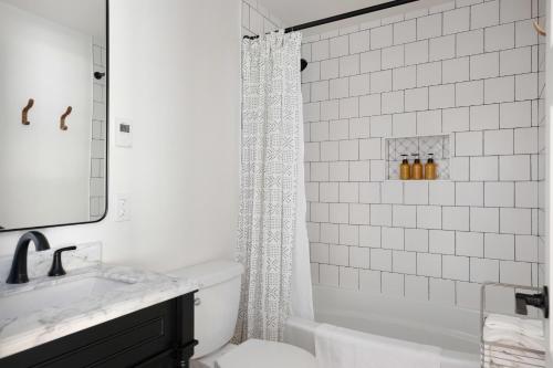 a white bathroom with a shower curtain and a sink at Perch - Greenbank Cottage in Greenbank