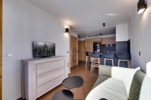 un salon avec un canapé et une télévision dans l'établissement Jardins de Val Le charme à la Montagne, à Val dʼIsère