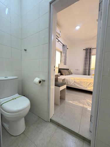 a bathroom with a toilet and a bedroom with a bed at Ann Luxurious Apartments 6 in Accra
