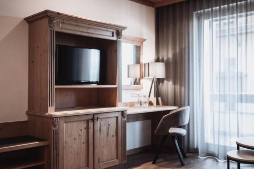 a room with a large entertainment center with a television at Hotel Montis - Schönblick in Brunico