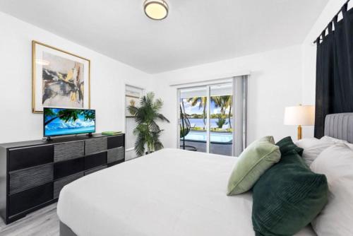 a white bedroom with a large bed and a television at Lake House in Miami