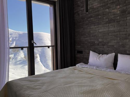 a bedroom with a bed and a window with snow at Luxury duplex with mountain views, new gudauri in Gudauri