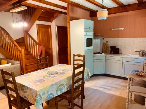 une cuisine avec une table et un réfrigérateur blanc dans l'établissement Gite du Pont de Pierre - au Moulin d'Eysus, à Eysus