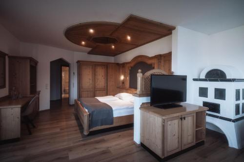 a bedroom with a bed and a flat screen tv at Hotel Montis - Schönblick in Brunico