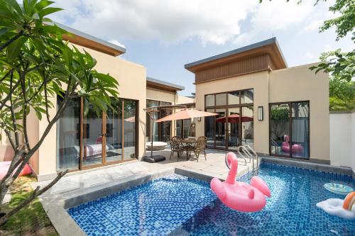 an image of a house with a swimming pool and pink inflatable flamingos at Iccssi Villa Haitang Bay Sanya in Sanya