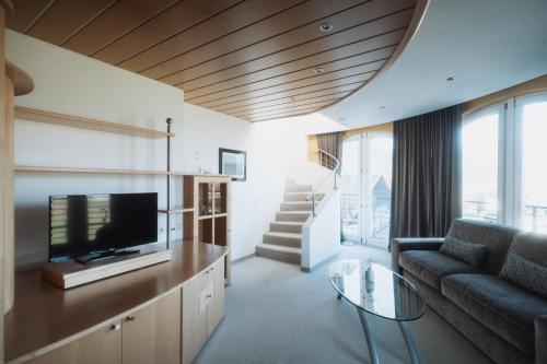 a living room with a couch and a tv at Hotel Montis - Schönblick in Brunico