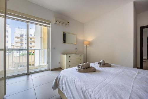 a white bedroom with a bed and a large window at Central Sliema Modern 2 bedroom Apartment Malta in Sliema