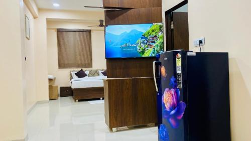 a living room with a tv and a refrigerator at Stay10 B&M LUXURY ACCOMDATION in Indore