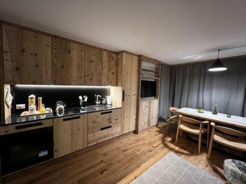 a kitchen with wooden cabinets and a table and a dining room at Monolocale 50mt da skilift Cascata Et Cristallo Studio Apartment in Madesimo