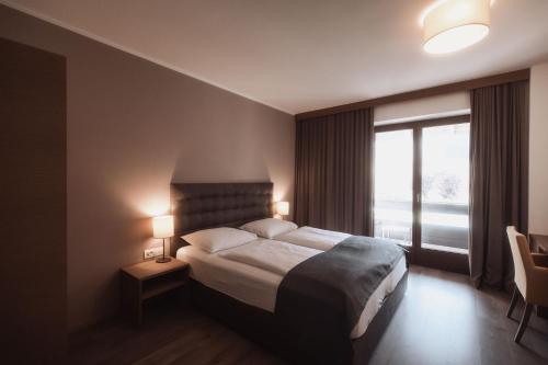 a hotel room with a bed and a window at Hotel Montis - Schönblick in Brunico