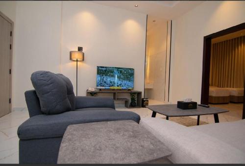 a living room with a blue chair and a tv at princes house in Jeddah