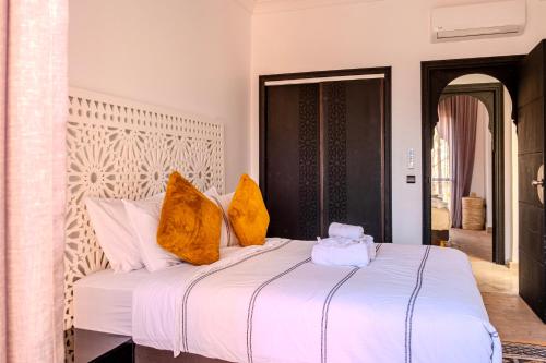 a bedroom with a white bed with yellow pillows at Luxury Villa with Pool, Garden & Gated Security in Marrakech