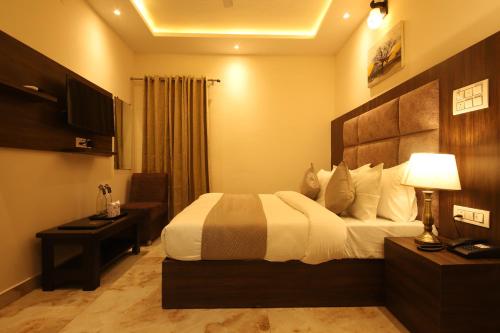 a hotel room with a bed and a desk and a television at Perfectstayz Value Dhruv Nanda near Haridwar Railway Station in Haridwār