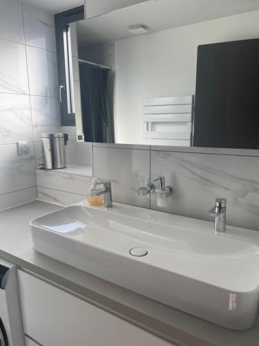 une salle de bain avec un lavabo blanc et un miroir dans l'établissement Appartement moderne et cosy, à Marseille