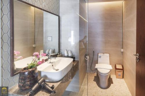 a bathroom with a sink and a toilet and a mirror at Apec Mandala de Suite Mũi Né in Mui Ne
