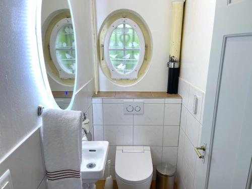 a small bathroom with two windows and a toilet at SwissHut Stunning Views Alps Lake Apart Kilinger in Oberhofen am Thunersee