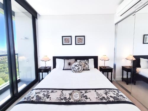 a bedroom with a large bed and large windows at Horizon Suite on the TOP in Olympic Park in Sydney