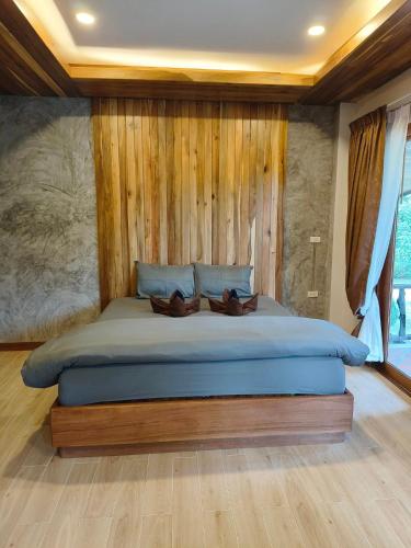 a bedroom with a large bed with a wooden wall at Dewshore Resort in Ban Tai