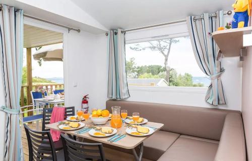 une salle à manger avec une table et des chaises et une fenêtre dans l'établissement Domaine Résidentiel de Plein Air Le Vorlen, à Fouesnant