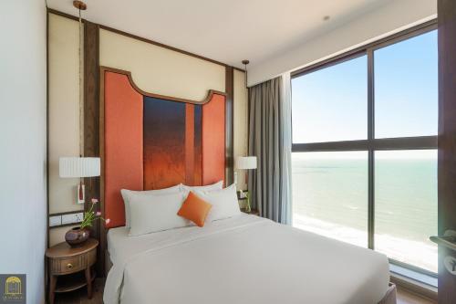 a bedroom with a large bed and a large window at Apec Mandala de Suite Mũi Né in Mui Ne
