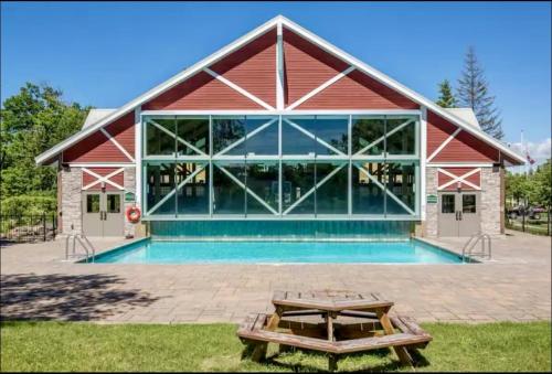 a large red building with a pool in front of it at Newly Renovated Ski-In Ski-Out 1-Bedroom Condo with Pool, Gym, Sauna by Horseshoe Valley in Edgar