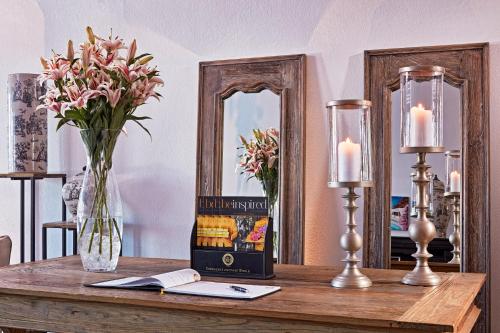 a table with a vase of flowers and two mirrors at San Antonio - Small Luxury Hotels of the World in Imerovigli