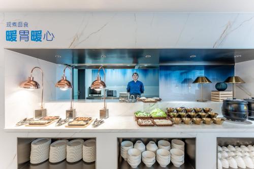 a person standing in a kitchen with food at Holiday Inn Express Haikou World Trade Center by IHG in Haikou