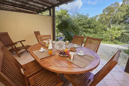 a wooden table with food and drinks on a patio at Villa Uzzo by Sicily Travelling Villas in Scopello