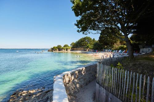 a beach with people swimming in the water at Au pied du GR 34 in Fouesnant