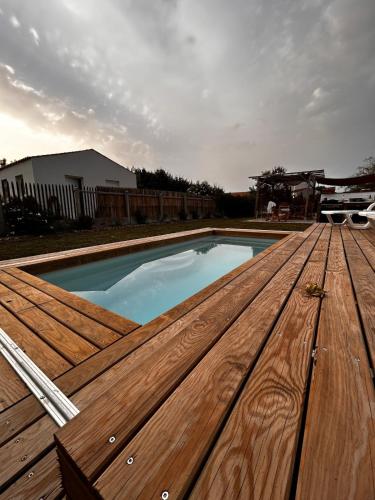 une piscine avec une terrasse en bois sur une maison dans l'établissement Maison Ginette - Piscine chauffée, 8 pers, proche de la mer, à Saint-Georges-dʼOléron