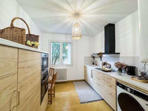 - une cuisine avec des murs blancs et des placards en bois dans l'établissement Le Muret, à Toulouse