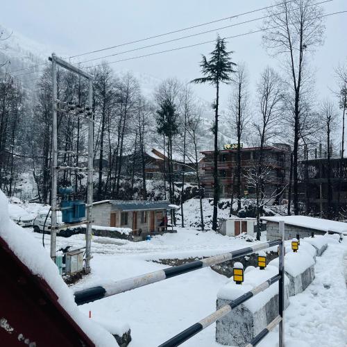 a snow covered city with a building and buildings at Ekaant Stays - Manali in Manāli