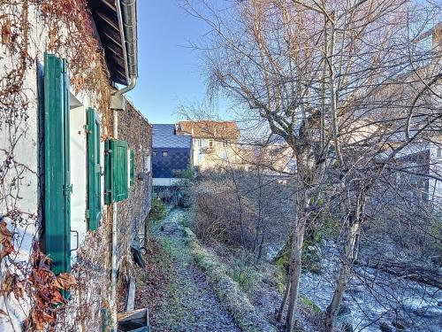 a building with green shuttered windows and a tree at Maison des Bains in Allevard