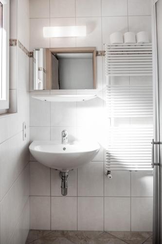 a white bathroom with a sink and a mirror at Ferienhaus Rehhaus in Holzgau