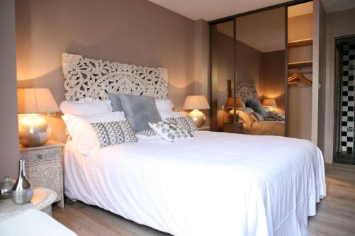 a bedroom with a large white bed and a mirror at Hotel La Villa Julia in Agon Coutainville