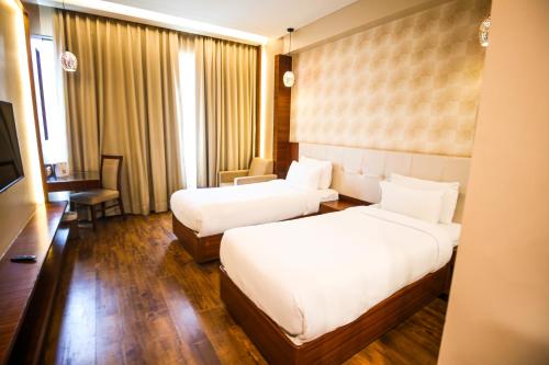 a hotel room with two beds and a television at Pristine Hotel, Varanasi in Varanasi