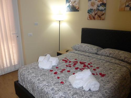 a bed with red roses on it with towels and towels at La Villetta nel Parco in La Giustiniana