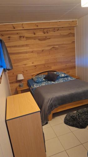 a bedroom with a bed with a wooden wall at Gîte l'hippocampe in Jarjayes