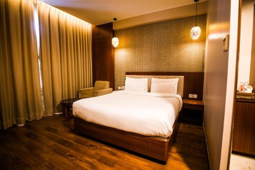a hotel room with a bed and a table at Pristine Hotel, Varanasi in Varanasi