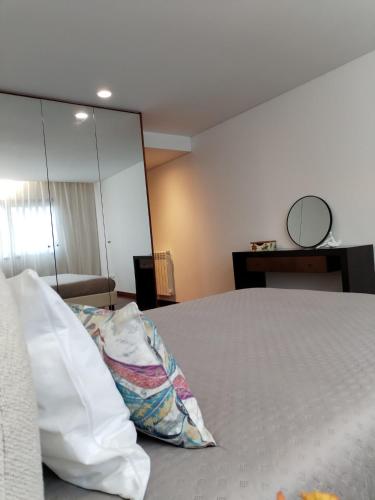 a bedroom with a bed with a pillow and a mirror at Apartamento Centro Guimarães com Vista Panorâmica in Creixomil