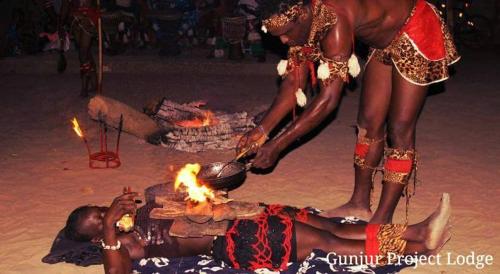 a woman laying on the ground in front of a fire at The Gunjur Project Lodge in Gunjur