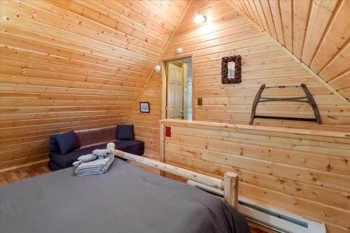 a log cabin bedroom with a bed and a chair at Perch - Antler House in Ashford