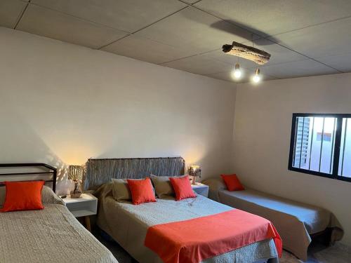 a bedroom with two beds with red pillows at Alojamiento Piedra y Camino Tilcara in Tilcara
