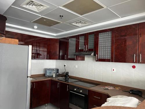 een keuken met bruine kasten en een wit betegeld plafond bij Opal Tower in Dubai