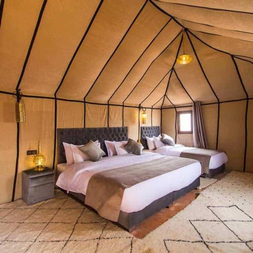 a bedroom with two beds in a tent at Merzouga heart camp in Merzouga