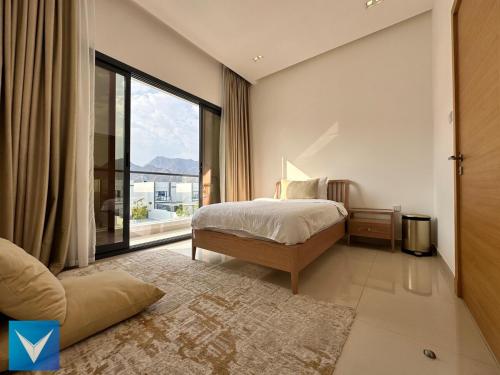 a bedroom with a bed and a large window at 3BR Modern Seashore Private Villa with swimming Pool in Fujairah