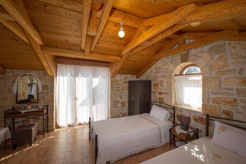 a bedroom with two beds and a stone wall at Fioro Stone House in Tsilivi