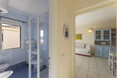 ein Bad mit einer Dusche und ein Schlafzimmer mit einem Bett in der Unterkunft Golfo Aranci Apartments With Ac in Marinella
