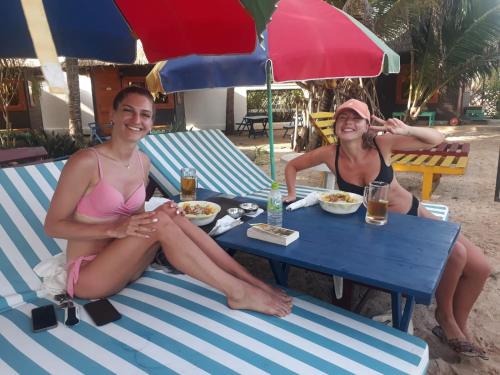 two women in bathing suits sitting at a table on the beach at Tomorrowland Beach Villas in Tangalle